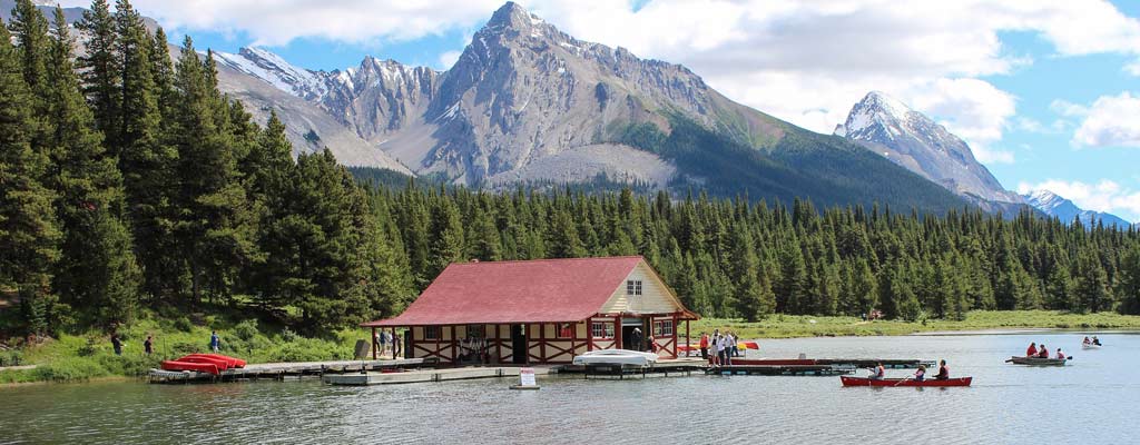 a small marina sits near a mountain, with kayakers in the water