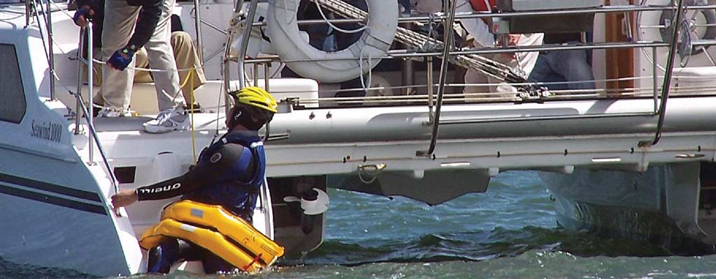 a man is pulled out of the water practicing crew overboard techniques