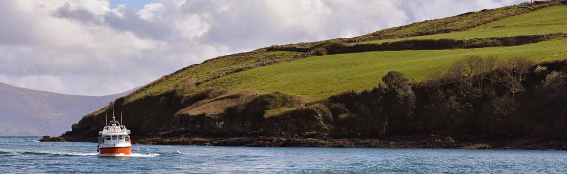 A boat powers by a hilly shoreline