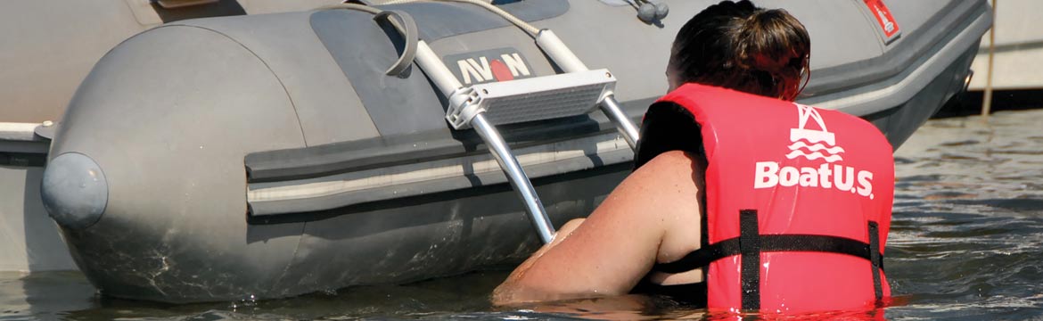 A woman climbs a ladder on an inflatable dinghy
