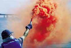 From the stern of a boat, an orange smoke is tested in day light near the Chesapeake Bay Bridge