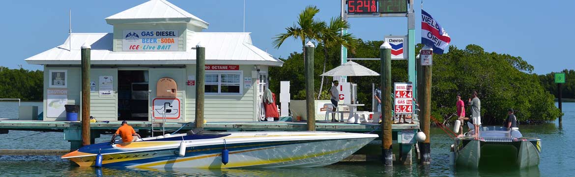 Two boats dock at a fuel station on a sunny day