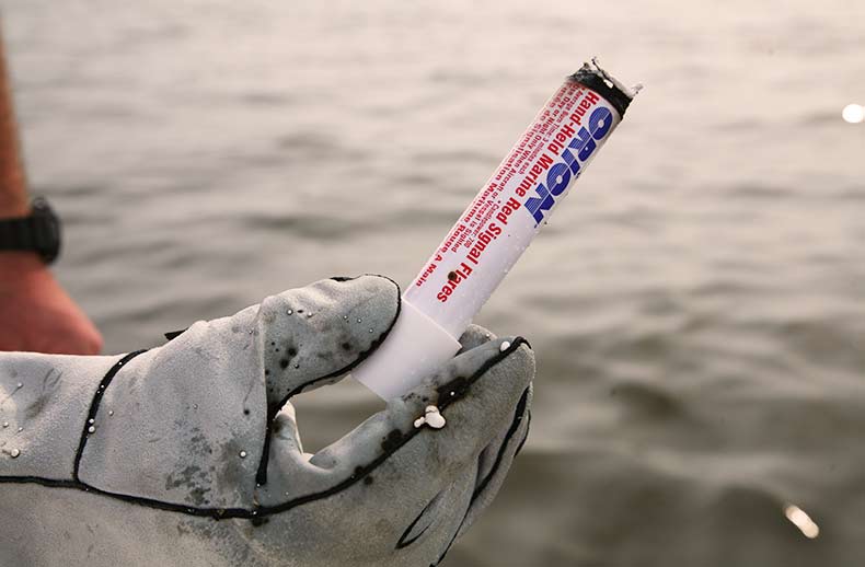 A tester is holding a used flare which has burnt far down. The tester is using a glove for protection.