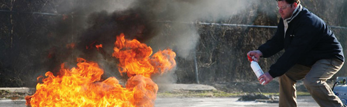 A man aims his fire extinguisher at a flame