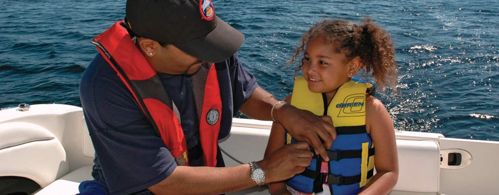 a man adjusts a girl's life jacket