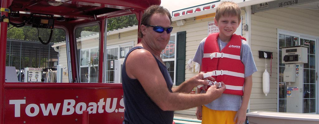 towboat operator fitting a life jacket to a child