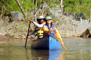 a couple people paddle a canoe