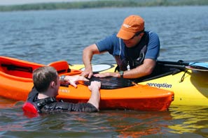 a man helps someone who has capsized his kayak