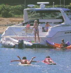 a number of people playing in the water behind a large yacht
