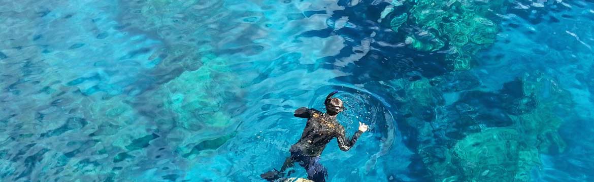 a man snorkeling in bright blue water