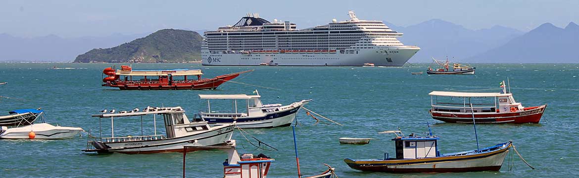 fishing trawlers moored while a cruise vessel passes in the distance